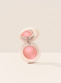 Cheer| Rare Beauty's Soft Pinch Luminous Powder Blush in the shade Cheer opened against a neutral background.