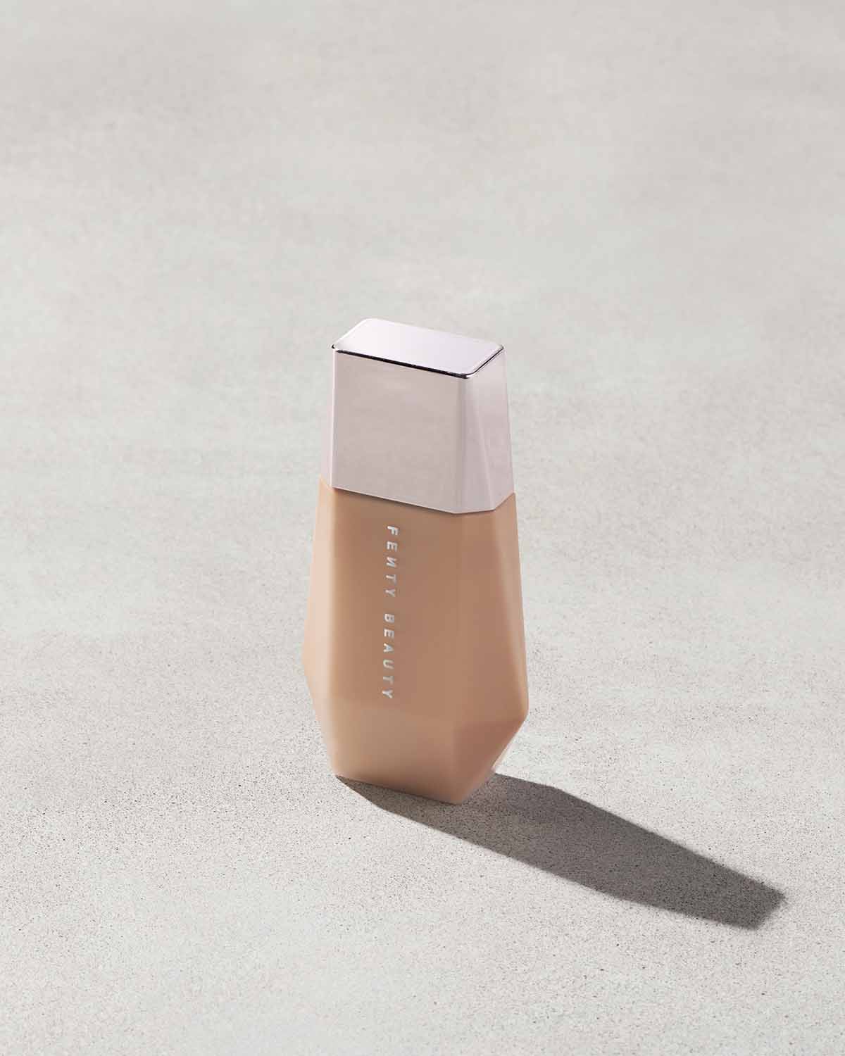 Eaze Drop’Lit All-Over Glow Enhancer shown in shade Honey Citrine on a concrete background. 